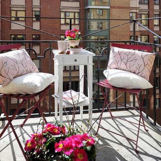 Ιδέες καλοκαιρινής διακόσμησης λουλουδιών διακοσμούν τα λουλούδια του μπαλκονιού σε γλάστρες δύο καρέκλες ψηλά τραπεζάκια μαξιλάρια