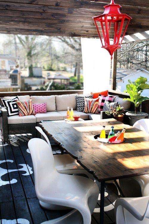 Καλοκαιρινό πάρτι στα σκεπαστή βεράντα ξύλινο τραπέζι ακρυλικές καρέκλες μαξιλάρια πάγκου