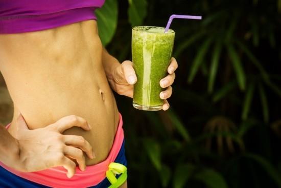Σπορ κορίτσι που κρατά ένα πράσινο smoothie Τα smoothies γυμναστικής είναι μοντέρνα