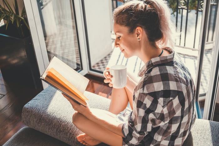 Ζώδιο ευτυχισμένο μόνο ανεξάρτητο μοναχικό νεαρό κορίτσι που διαβάζει ένα βιβλίο στο σπίτι πίνοντας καφέ