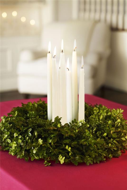 Ιδέες διακόσμησης τραπεζιού για χριστουγεννιάτικο στεφάνι από γρασίδι από πράσινα κλαδιά κισσού που καίνε λευκά κεριά