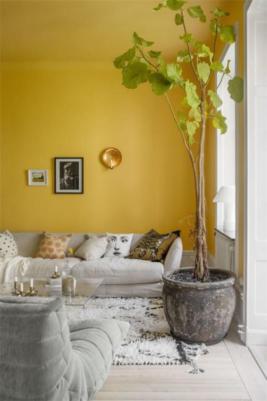 Trend χρώματα 2021 στον εσωτερικό τοίχο προφοράς στο φωτεινό κίτρινο κομψό σαλόνι ψηλό φυτό εσωτερικού χώρου