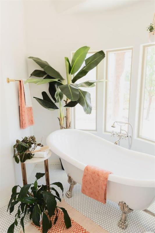 Τροπική διακόσμηση στο μπάνιο Αίσθηση ζούγκλας, ασορτί φυτά μπάνιου, μεγάλα πλούσια φύλλα, ροζ πετσέτες, μπανιέρα με νύχια