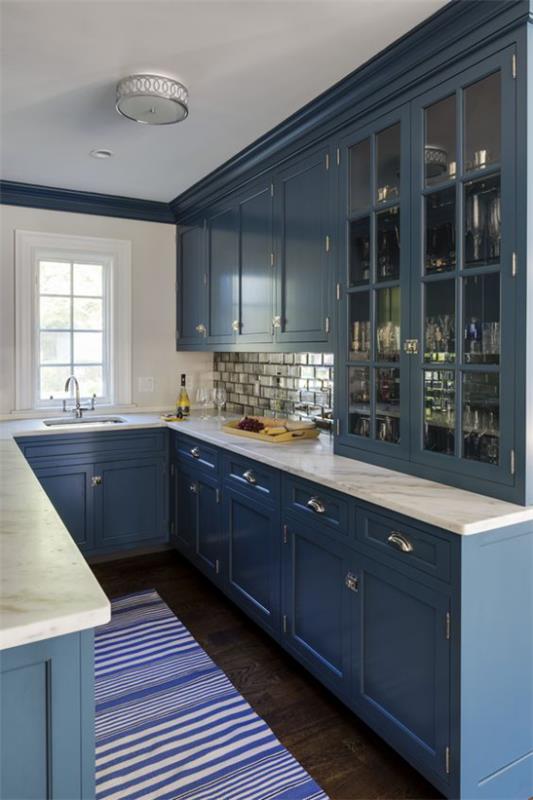 Υπόγεια κουζίνα σκούρα μπλε ντουλάπια κουζίνας ριγέ δρομέας μικρό παράθυρο λευκοί πάγκοι
