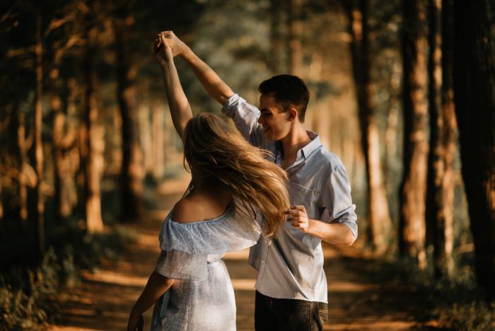 Ερωτευμένο το ευτυχισμένο νεαρό ζευγάρι του χορεύει στο δάσος φορώντας ροζ γυαλιά