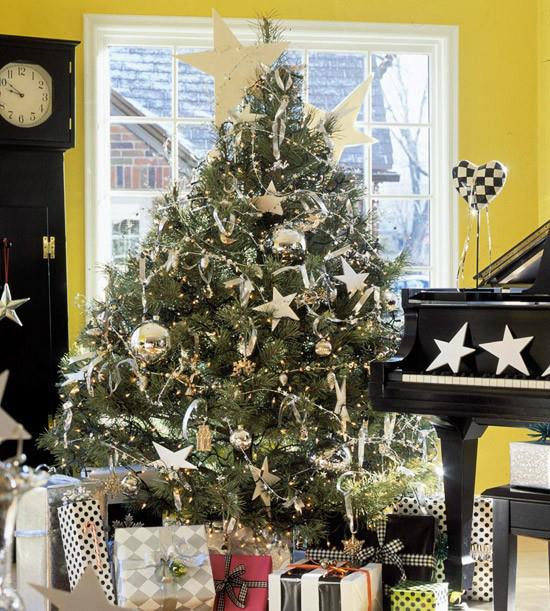 Χριστουγεννιάτικο δέντρο στολίζει σε λευκό και ασημί κλασικό χριστουγεννιάτικο δέντρο χρυσά κοσμήματα πολυάριθμα τυλιγμένα δώρα δίπλα στο πιάνο