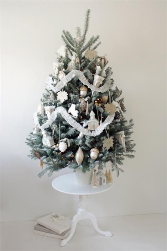 Χριστουγεννιάτικο δέντρο στολίζει όμορφα διακοσμημένο σε λευκό και ασημί μικρό χριστουγεννιάτικο δέντρο τοποθετημένο σε μικρό στρογγυλό τραπέζι