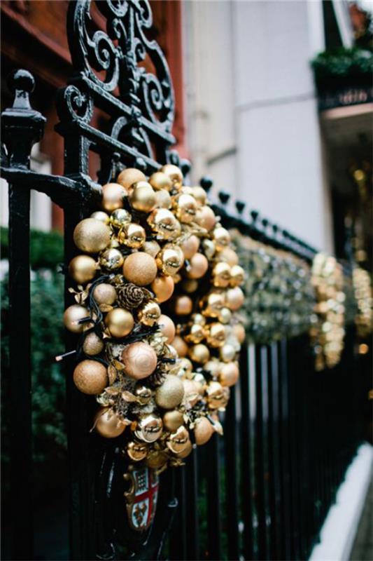 Χριστουγεννιάτικη διακόσμηση σε χρυσό και μαύρο στεφάνι από χρυσές χριστουγεννιάτικες μπάλες σε φόντο μαύρου φράχτη