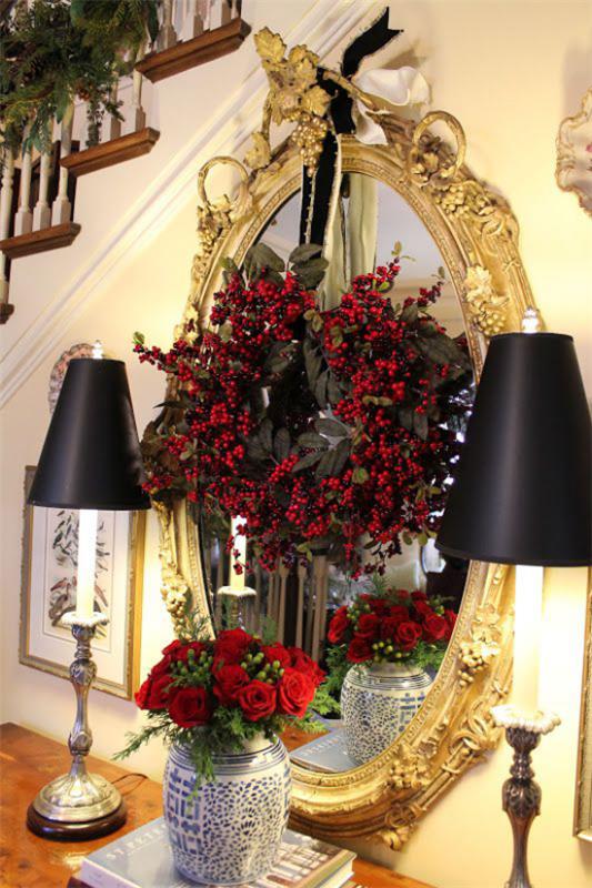 Χριστουγεννιάτικα στολίδια σε χρυσό και μαύρο στο διάδρομο με τόνους σε χρυσό και μαύρα κόκκινα τριαντάφυλλα στο βάζο μπροστά στον καθρέφτη