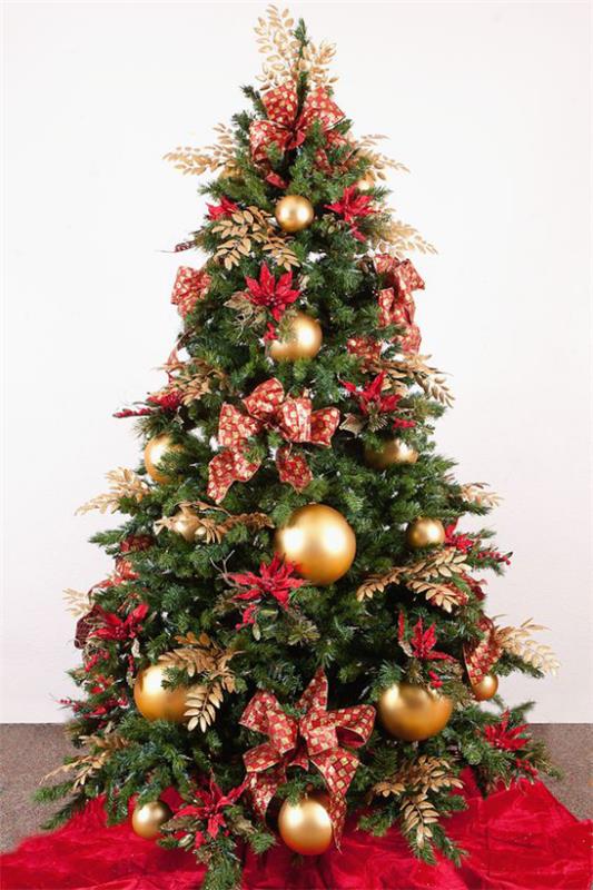 Χριστουγεννιάτικα στολίδια σε κόκκινο και χρυσό Χριστουγεννιάτικο δέντρο στολισμένο στη γωνία δίπλα στο τζάκι