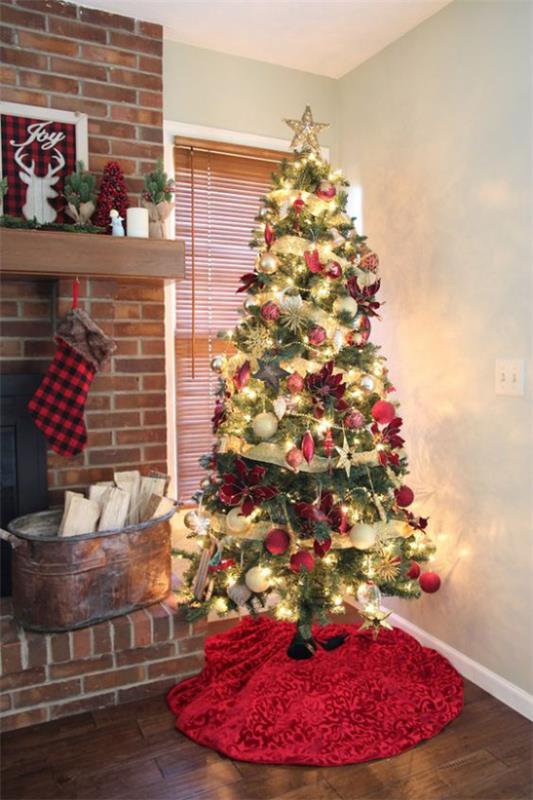 Χριστουγεννιάτικα στολίδια σε κόκκινο και χρυσό Χριστουγεννιάτικο δέντρο όμορφα διακοσμημένο στη γωνία δίπλα στο τζάκι έντονα χρώματα