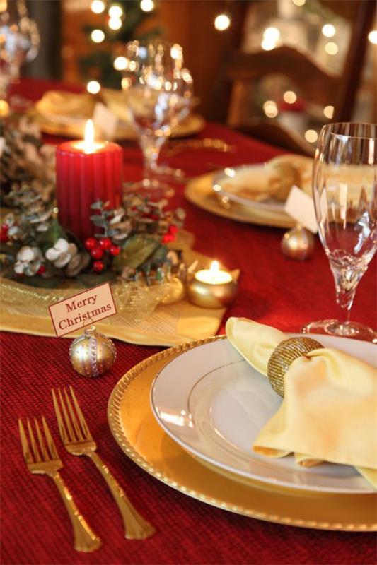 Χριστουγεννιάτικη διακόσμηση σε κόκκινο και χρυσό γιορτινό τραπέζι κόκκινο τραπεζομάντιλο ψιλή πορσελάνη επιχρυσωμένο μαχαιροπίρουνο κόκκινο κερί