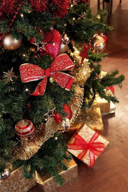 Χριστουγεννιάτικες διακοσμήσεις σε κόκκινες και χρυσές μεγάλες κόκκινες φιόγκο μπάλες γιρλάντες πολλά δώρα κάτω από το χριστουγεννιάτικο δέντρο