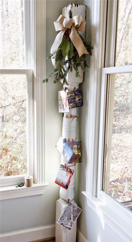 Συνδέστε χριστουγεννιάτικες κάρτες σε ξύλινη κολόνα με πράσινο έλατο και φιόγκο