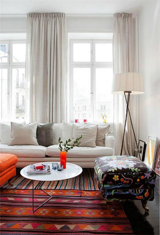 Το σαλόνι επεκτείνει οπτικά λευκό καναπέ λευκές κουρτίνες κυριαρχεί πολύ πορτοκαλί πολύχρωμο χαλί