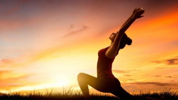 Yoga Surya Namaskar χαιρετισμός ήλιου στην παραλία με την ανατολή