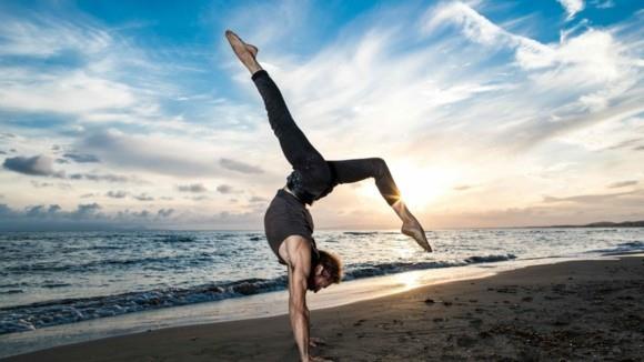 Yoga Surya Namaskar χαιρετισμός ήλιου στην παραλία στο ηλιοβασίλεμα