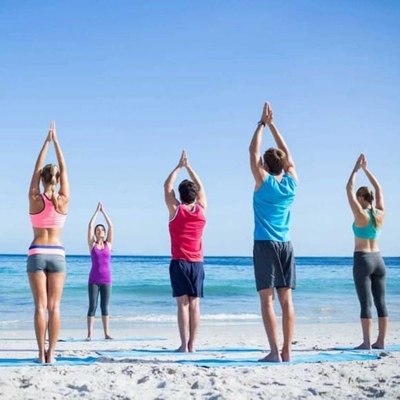 Γιόγκα χαιρετισμός στον ήλιο Surya Namaskar στην παραλία