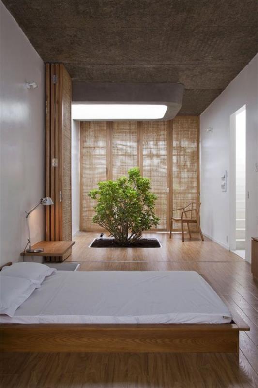 Ζεν υπνοδωμάτιο φαρδύ κρεβάτι ύπνου ανοιχτόχρωμο λινό πολύ ξύλο μεγάλο σκοτεινό παράθυρο μια μικρή δέντρο πράσινη νότα