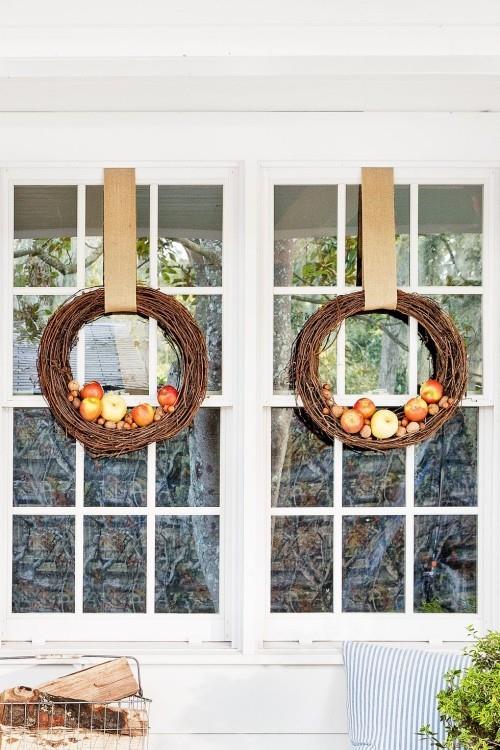 Δύο φθινοπωρινά στεφάνια στο παράθυρο της βεράντας μήλα καρύδια συνυφασμένα κλαδιά