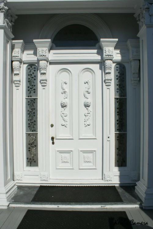 παλιομοδίτικα διακοσμητικά μοτίβα διακοσμούν το λευκό σχέδιο της μπροστινής πόρτας