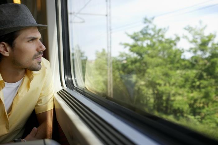 άντρας που ταξιδεύει με τρένο κοιτάζοντας μέσα από το παράθυρο