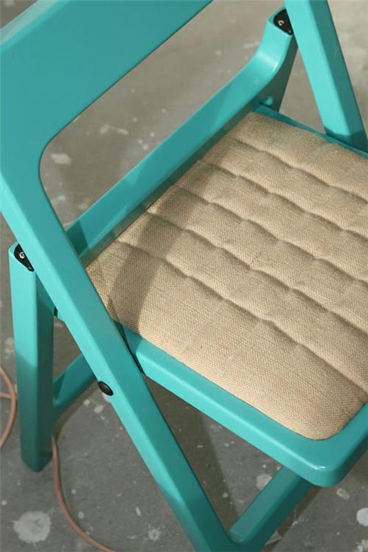 φωτιστικό δαπέδου και πτυσσόμενη καρέκλα σε ένα μαλακό μπεζ μαξιλάρι