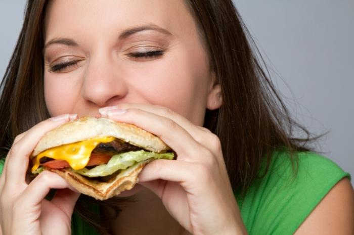 επιτυχημένη γυναίκα απώλειας βάρους που τρώει χάμπουργκερ