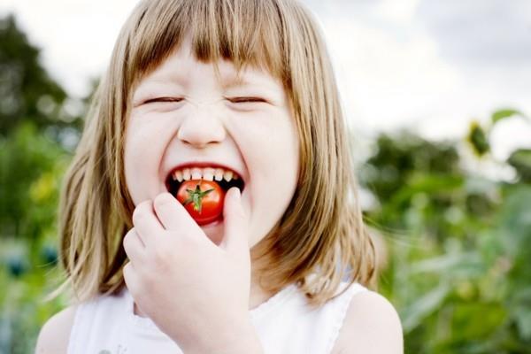 ευτυχισμένο παιδί με μια ντομάτα υγιεινά τρόφιμα παιδιά