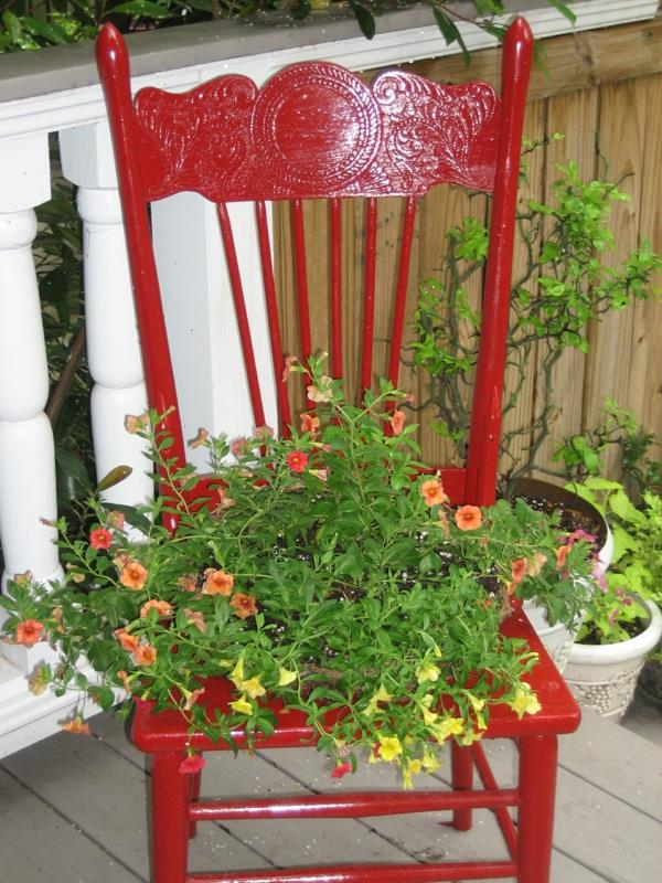 κήπος που διακοσμεί την παλιά κόκκινη φύτευση καρέκλας