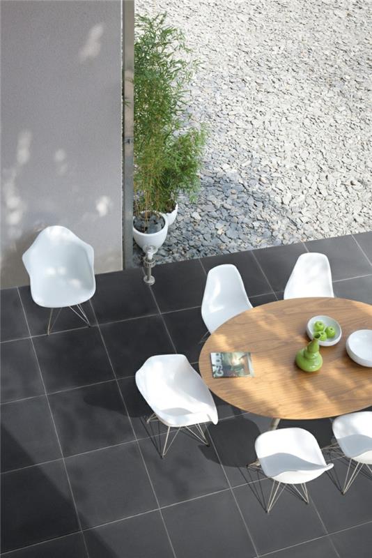 σχεδιασμός διαδρομών κήπου πλακάκια κήπου μαύρο κομψό στρογγυλό τραπέζι κήπου λευκές καρέκλες κήπου