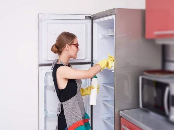 πλάγια όψη της γυναίκας που καθαρίζει το ψυγείο