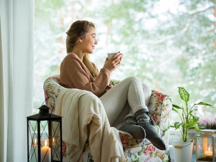 υγιείς και χαρούμενοι το χειμώνα μείνετε άνετοι στο σπίτι γυναίκα στην πολυθρόνα πιείτε τσάι χαλαρώστε ένα πράσινο φυτό δίπλα του