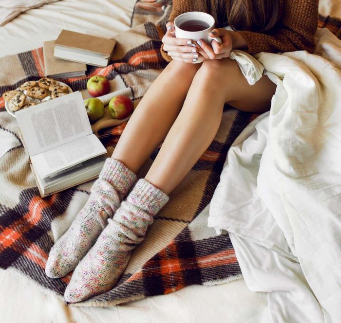 υγιή και χαρούμενη το χειμώνα νεαρή γυναίκα να μείνει στο κρεβάτι μικρά καραμέλα μήλα ζεστό τσάι ευχάριστη ζεστή ατμόσφαιρα