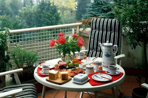 πλέγμα μπαλκόνι ζεστό στρογγυλό τραπέζι ρίγες μαύρα λευκά λουλούδια κόκκινο τραπέζι πρωινού