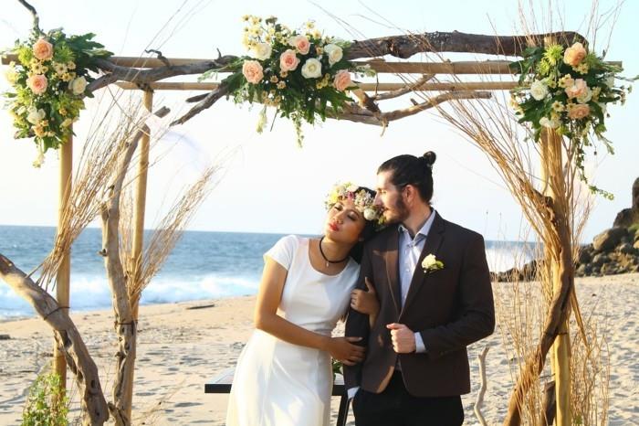 γάμος στην παραλία με νύφη και γαμπρό με αψίδα τριαντάφυλλου