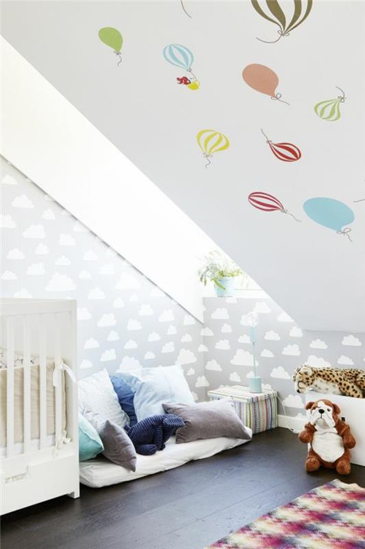 Παιδικό δωμάτιο με κεκλιμένη στέγη, βρεφικό δωμάτιο, βρεφικό κρεβάτι, ζεστή γωνιά, χώρος παιχνιδιού, χαριτωμένα παιχνίδια, μπαλόνι, ταπετσαρία, σύννεφα