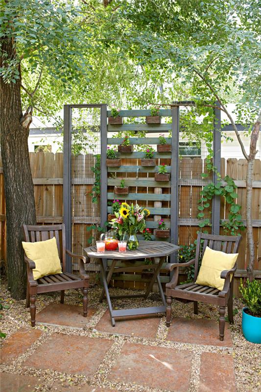 ο μικρός κήπος δημιουργεί μια ζεστή, φιλόξενη γωνιά για να χαλαρώσετε στη σκιά που βρίσκεται ακριβώς πάνω στο φράχτη του κήπου