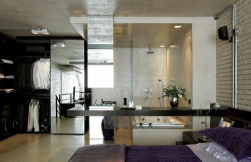 Μικρό διαμέρισμα που δείχνει τοίχο από τούβλα σε λευκό μοβ κρεβάτι
