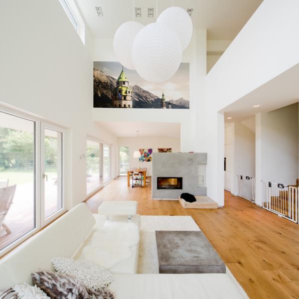 μοντέρνο σαλόνι σε δύο επίπεδα κομψό εσωτερικό σχεδιασμό σε λευκά κρεμαστά φώτα τοιχογραφία ανοιχτόχρωμο ξύλο στο πάτωμα τσιμεντένιο τοίχο με τζάκι