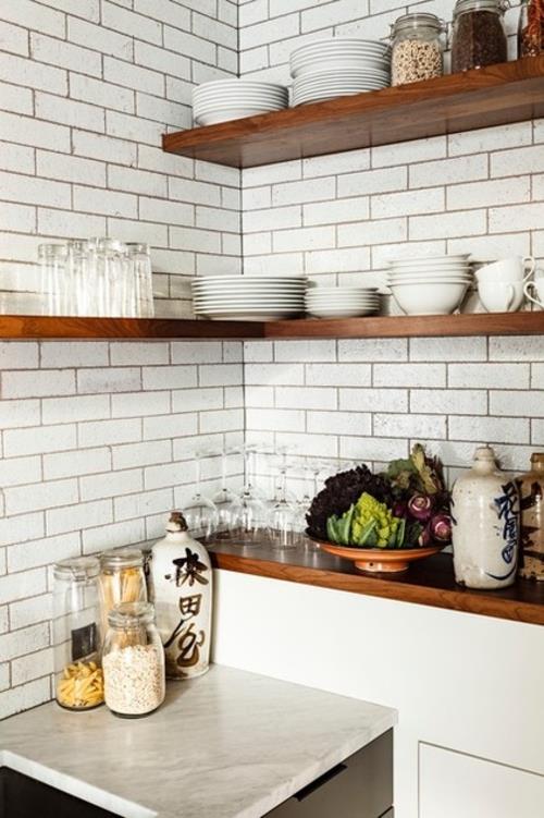 ανοιχτά ράφια κουζίνας στον γωνιακό τοίχο από τούβλα σε λευκό χρώμα