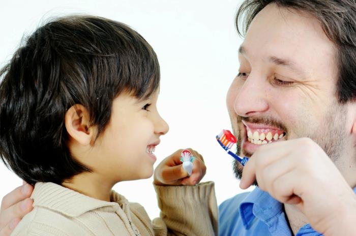σωστή οδοντιατρική φροντίδα πατέρας και γιος βουρτσίζουν τα δόντια τους