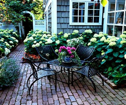 σκιασμένο καθιστικό στον κήπο μεταλλικές καρέκλες δομές λουλουδιών