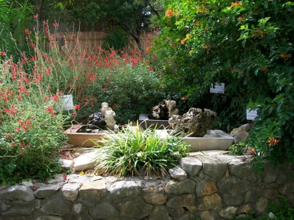 πέτρινος τοίχος κήπος φράχτης κόκκινα λουλούδια κήπος μοντέρνος