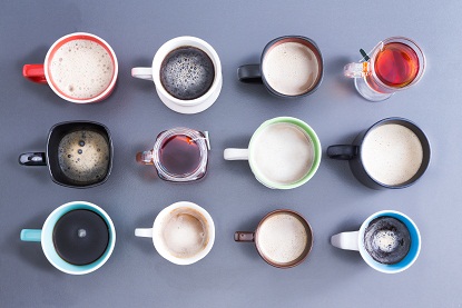 Gri üzerine sıcak taze çay ve kahve ile doldurulmuş on iki farklı fincan, kupa ve bardaktan oluşan düzgün bir düzenlemenin üstten görünümü ile günlük kafein dozunuzun zamanını gösteren kavramsal görüntü