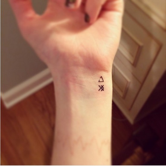 Mažos trikampio geometrinės tatuiruotės ant riešo