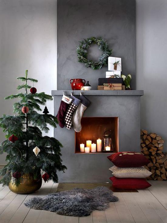 ονειρεμένες χριστουγεννιάτικες διακοσμήσεις στο σαλόνι μικρά χριστουγεννιάτικα δέντρα τζάκια κεριά γκρι φόντο βιομηχανικό στυλ