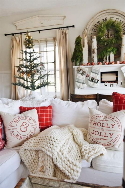 ονειρική χριστουγεννιάτικη διακόσμηση στο σαλόνι όμορφη διακόσμηση δωματίου φωτεινή ατμόσφαιρα Χριστουγεννιάτικο δέντρο κόκκινες προθέσεις μαλακά ριχτά μαξιλάρια κουβέρτας
