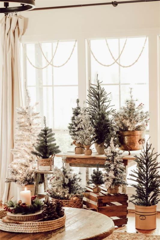 υπέροχη χριστουγεννιάτικη διακόσμηση στο σαλόνι, πολλά μικρά έλατα τοποθετημένα μπροστά στο παράθυρο