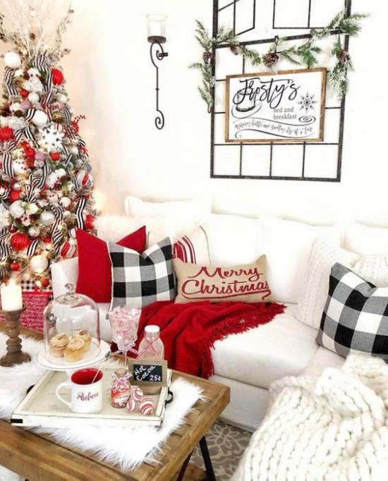 ονειρεμένες χριστουγεννιάτικες διακοσμήσεις στο σαλόνι λευκός καναπές κόκκινες πινελιές άνετα κουβέρτες μαξιλάρια έλατο αριστερά